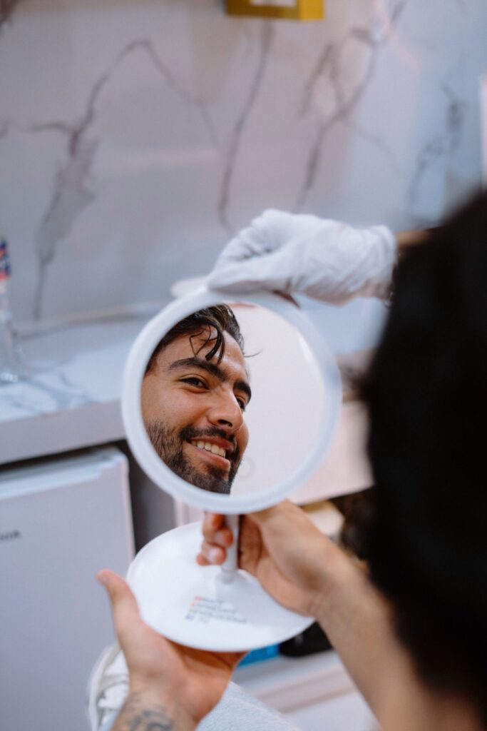 Man smiling at his reflection in a mirror